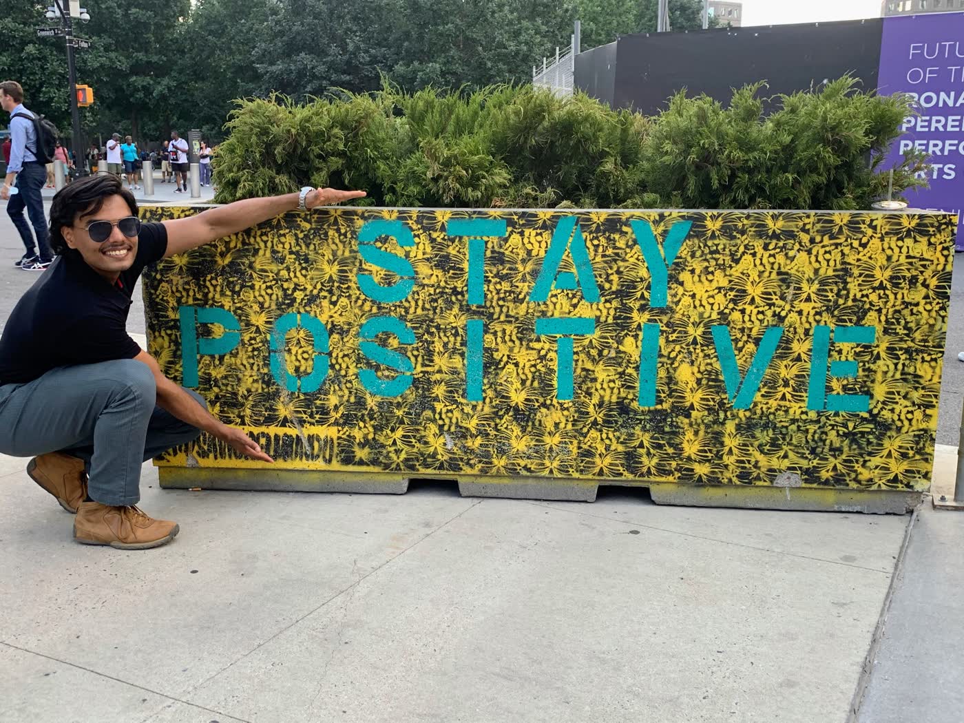 Vedant beside a colorful Stay Positive mural in New York City